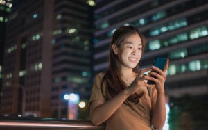 Young asian on public transportation platform using mobile investing ETF and fund bond saving at Central business distric