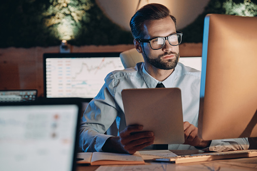 Confident young man working on computer while staying late in the office