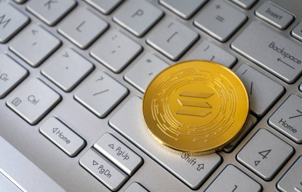 Solana single golden crypto coin on grey keyboard, close-up, copy space.