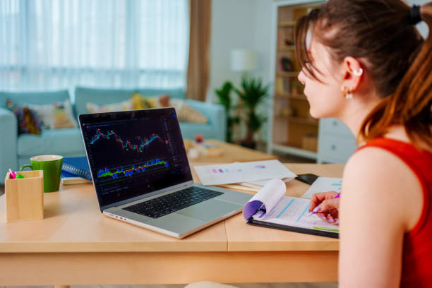 Young Businesswoman checking Bitcoin or stock market price chart on digital exchange on a laptop monitor computer at her desk at home, cryptocurrency future price action prediction. Stock Bitcoin ETF Trading.